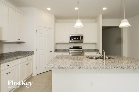 A kitchen with granite countertops and white cabinets.