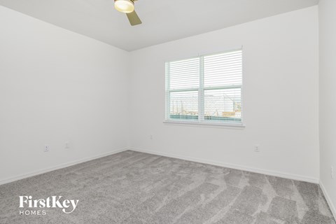 a bedroom with white walls and carpet and a window