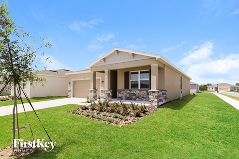 a beige house with a lawn and a driveway
