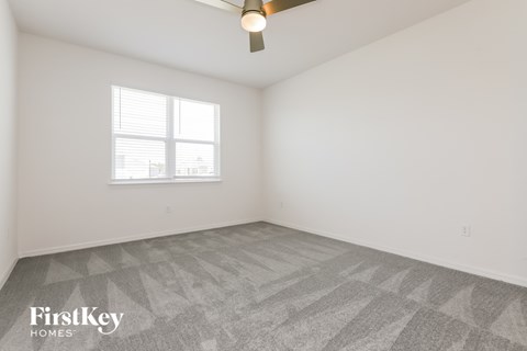 the living room of a home with white walls and a window