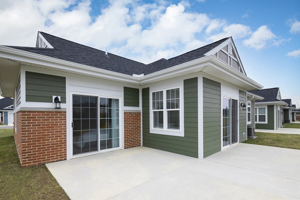 a house with green and white walls and a cement driveway