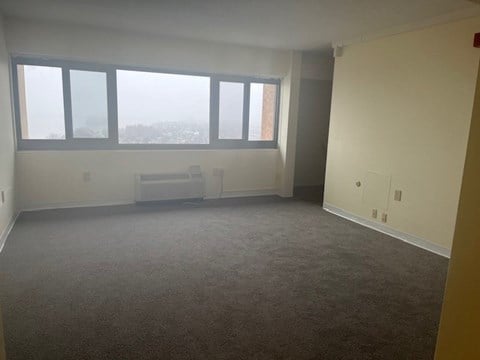 an empty living room with three large windows