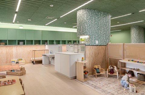 A child playing with blocks in a play area with a green wall.