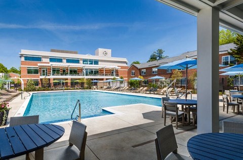 a swimming pool with tables and umbrellas in front of a building