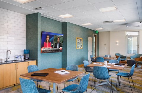 a conference room with tables and chairs and a screen on the wall