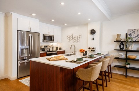 a kitchen with a large island and a stainless steel refrigerator