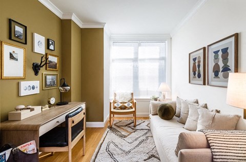 a living room with a couch and a desk and a window