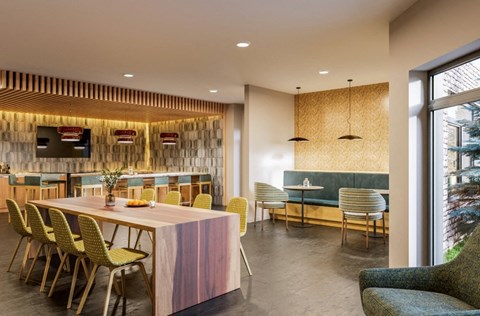 a dining area with a wooden table and chairs and a bar with yellow chairs