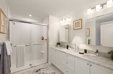 A white bathroom with a sink, mirror, and shower.