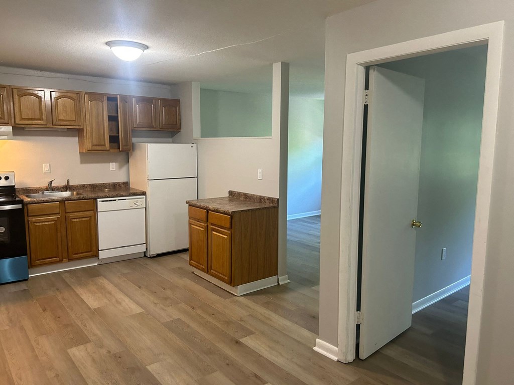 an empty kitchen with wooden floors and white appliances