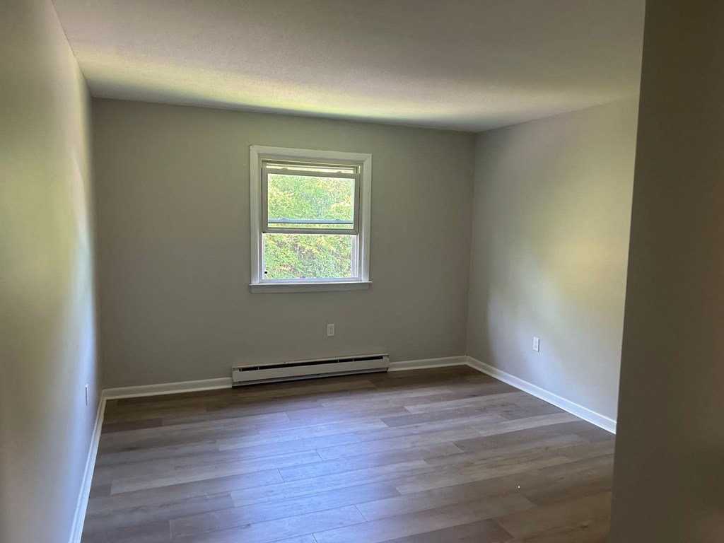 a empty room with a window and wooden floors
