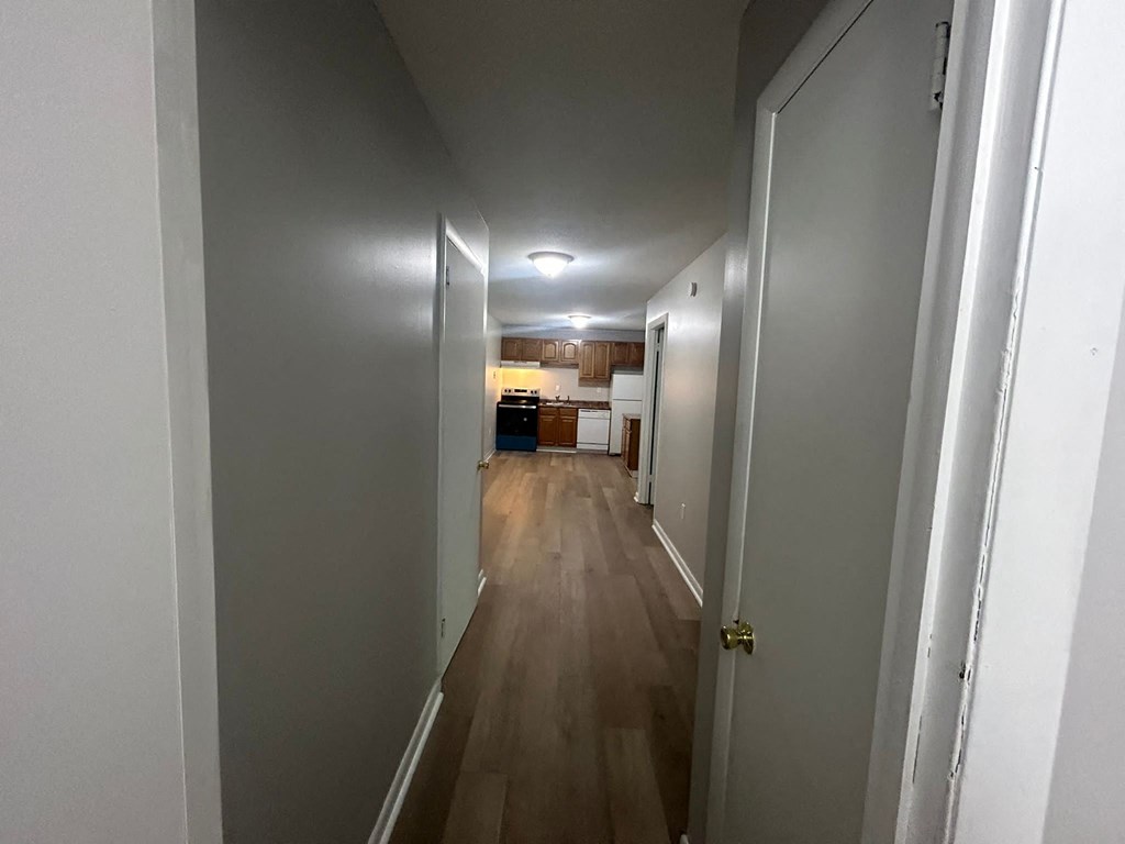 a long hallway with a door open to a kitchen