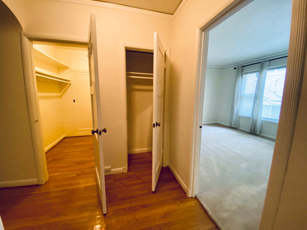 an empty room with doors open to a closet and a window