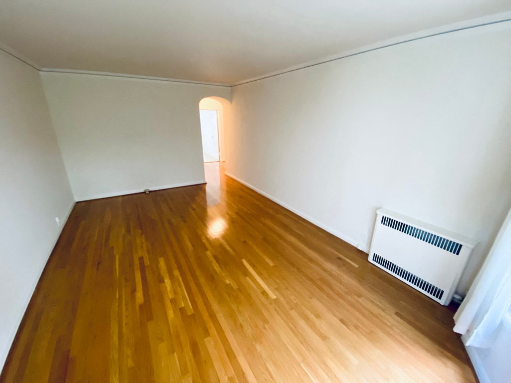 an empty living room with wooden floors and white walls