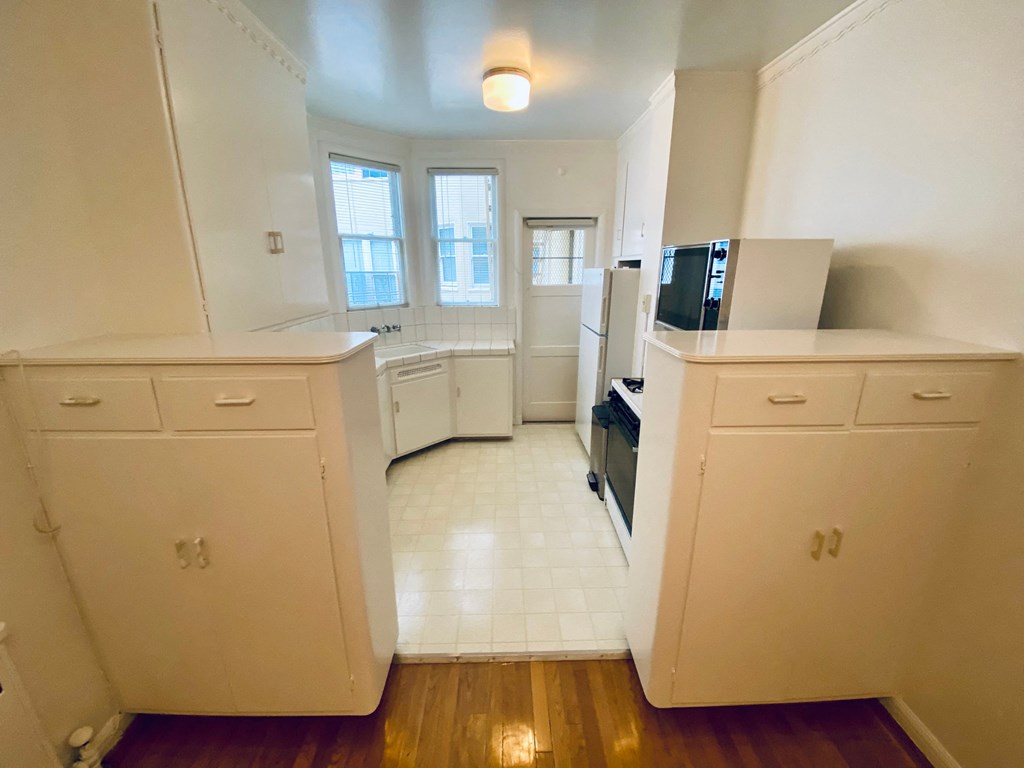 an empty kitchen with white cabinets and a window