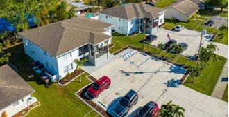 an aerial view of a house and a parking lot with cars