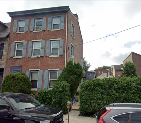 a tall brick building with cars parked in front of it