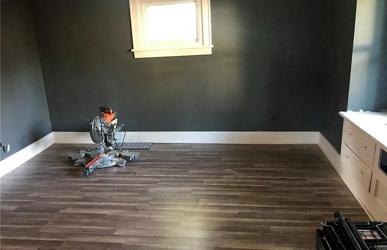 a man sitting on a chair in a room with wood floors