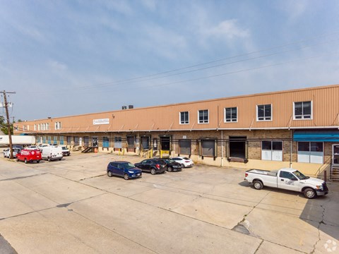A parking lot with a building in the background and several cars parked.