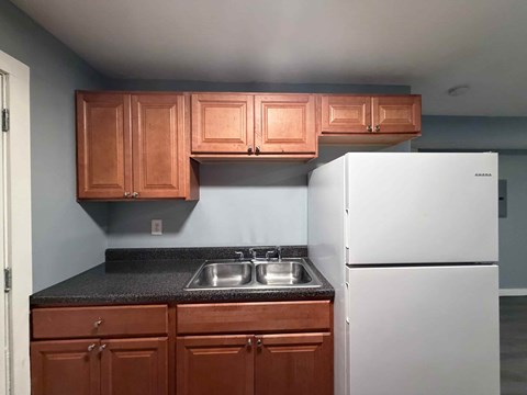 A kitchen with brown cabinets and a white refrigerator.
