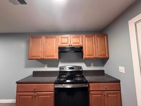 A kitchen with wooden cabinets and a black stove top.