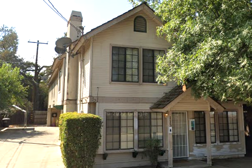 a white house with black windows and a tree