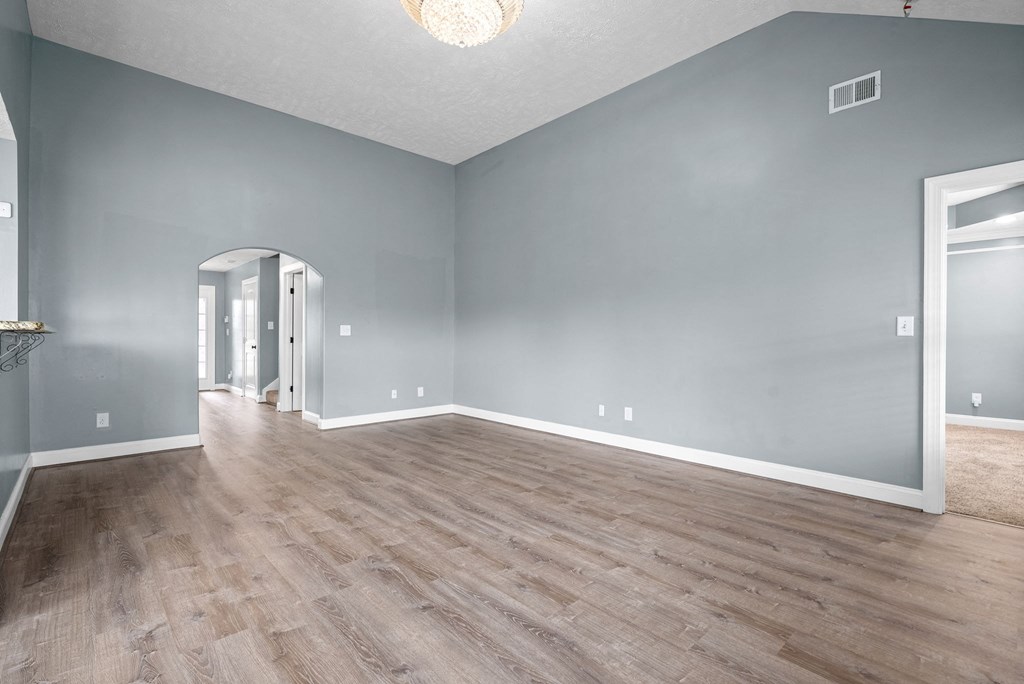 the living room and dining room of an empty house with wood flooring