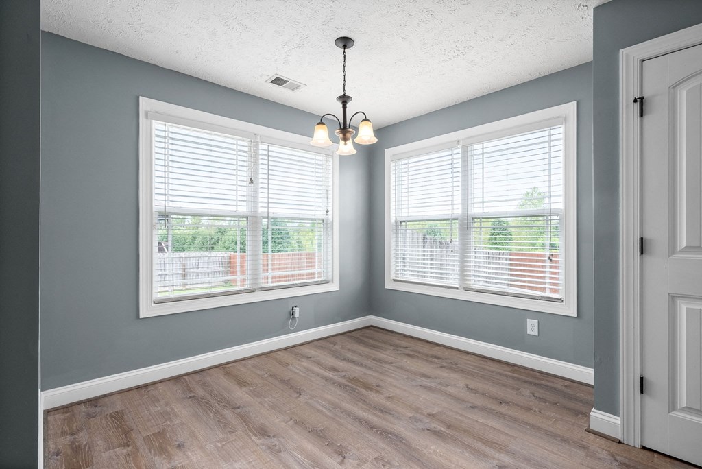 an empty living room with two windows and a wood floor