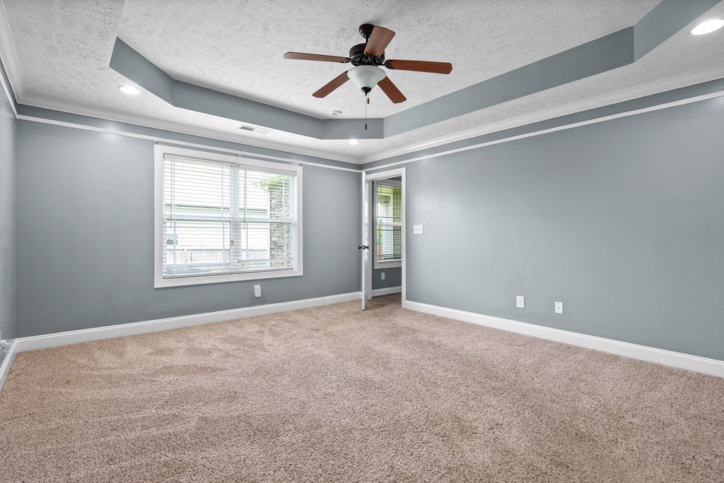 an empty living room with a ceiling fan and a window