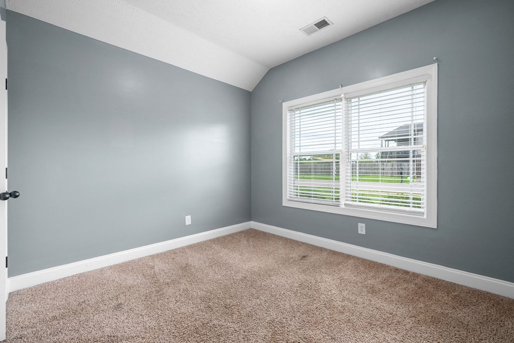 an empty bedroom with a large window and carpet