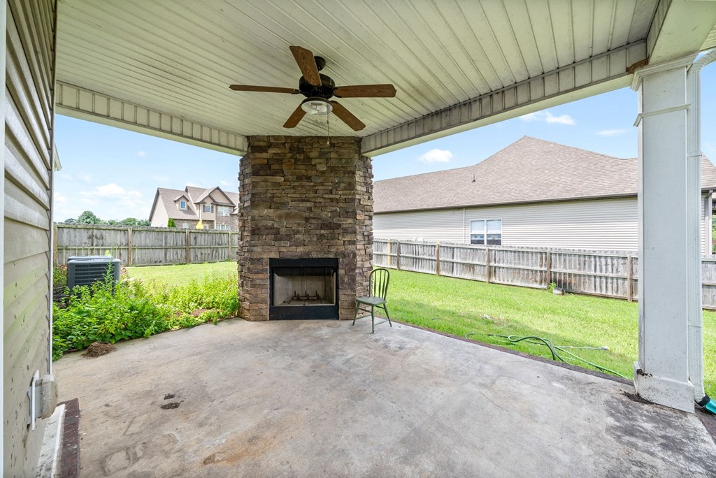 a covered patio with a fireplace and a ceiling fan