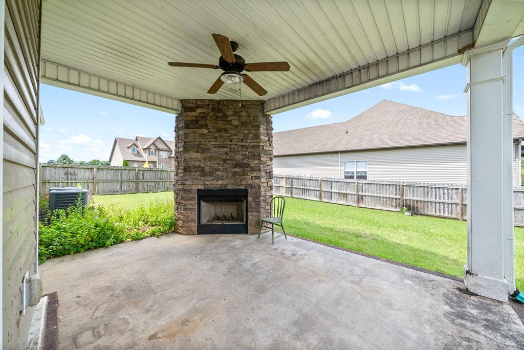 a covered patio with a fireplace and a ceiling fan