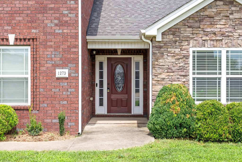 the front door of a brick house with a porch