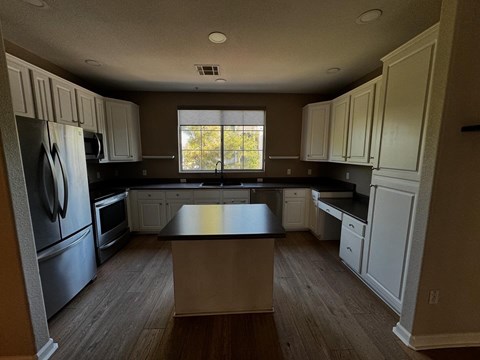 an empty kitchen with white cabinets and black counter tops