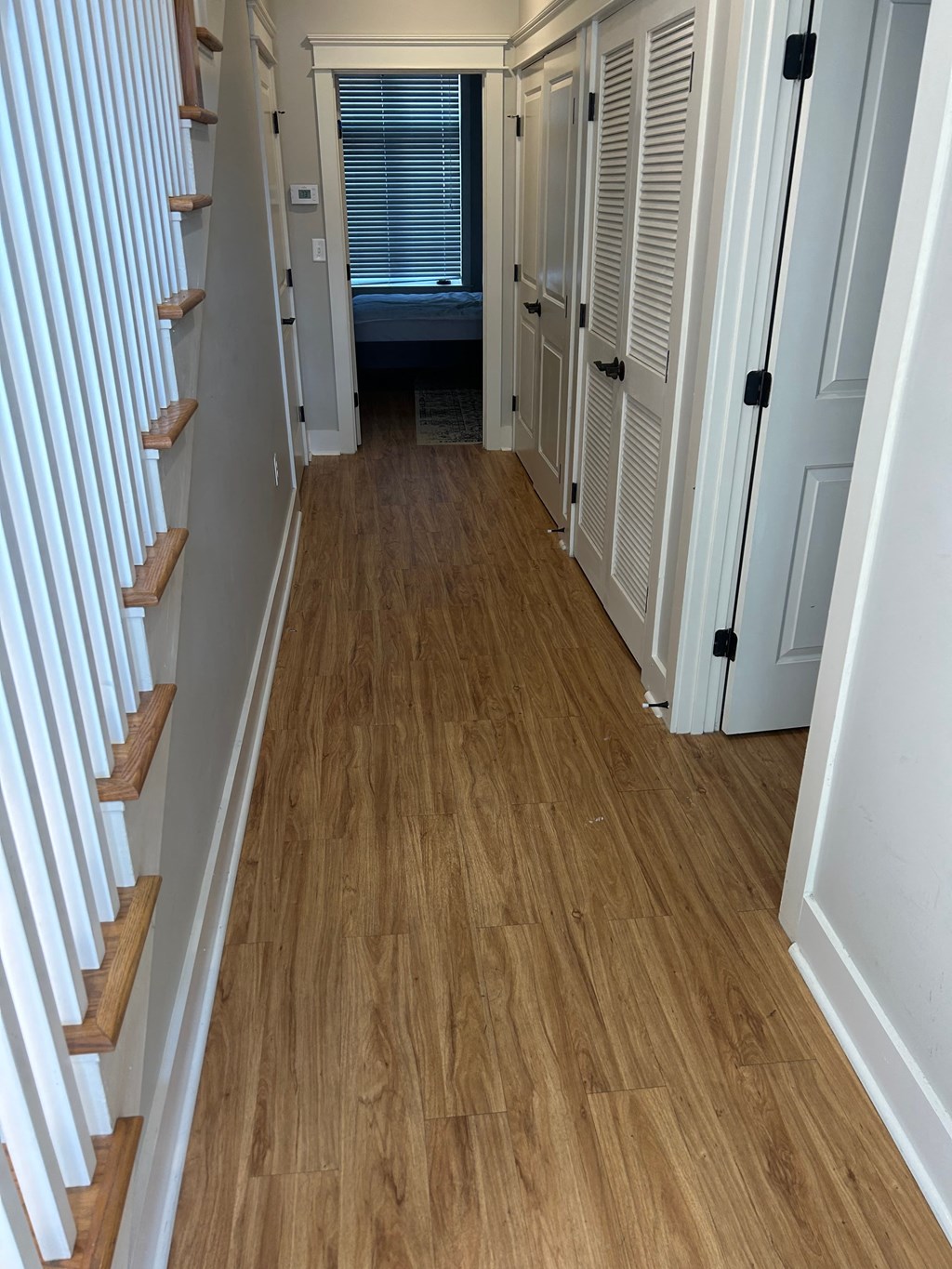 a small hallway with a hard wood floor and a staircase