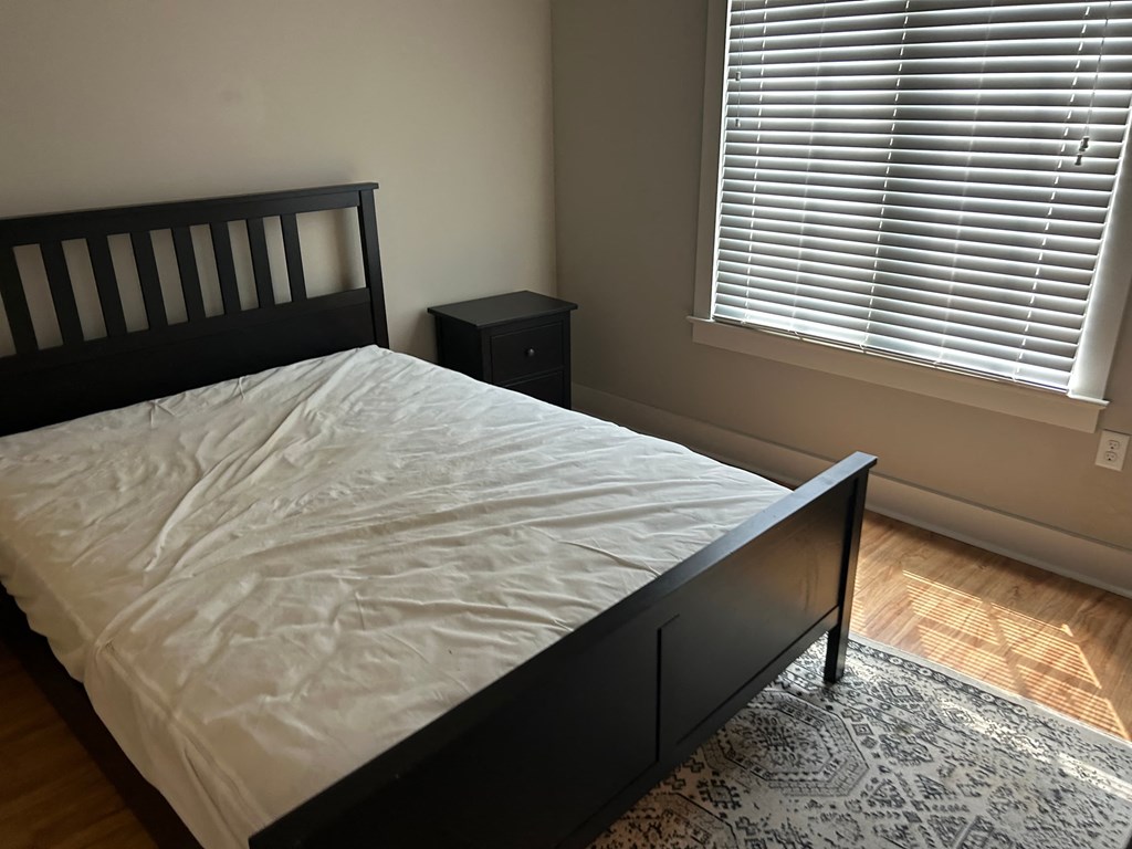 a bedroom with a bed and two windows with blinds