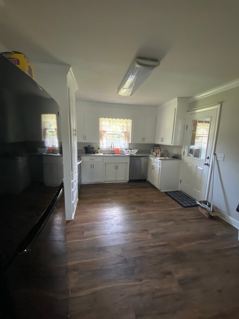 A kitchen with white cabinets and a black refrigerator.