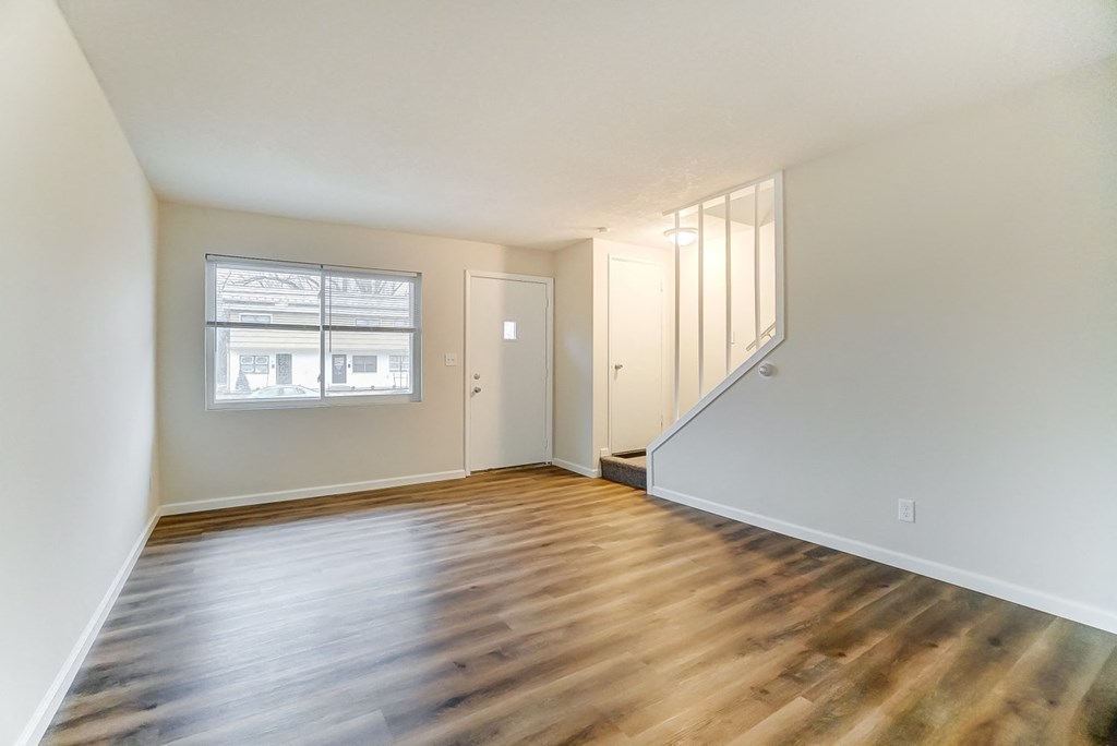 an empty living room with wood flooring and a window