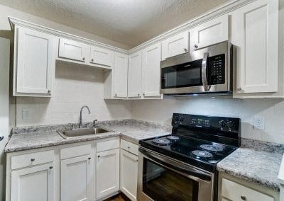 a kitchen with white cabinets and a stove and a microwave