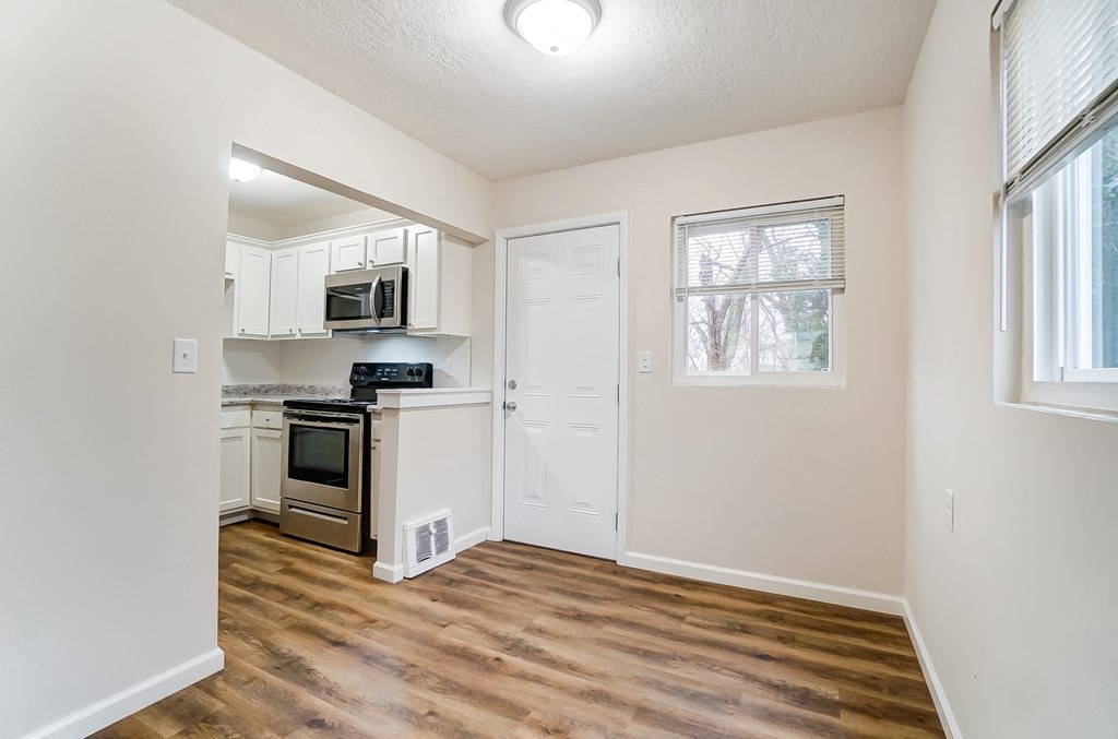 an empty kitchen with wood flooring and white cabinets
