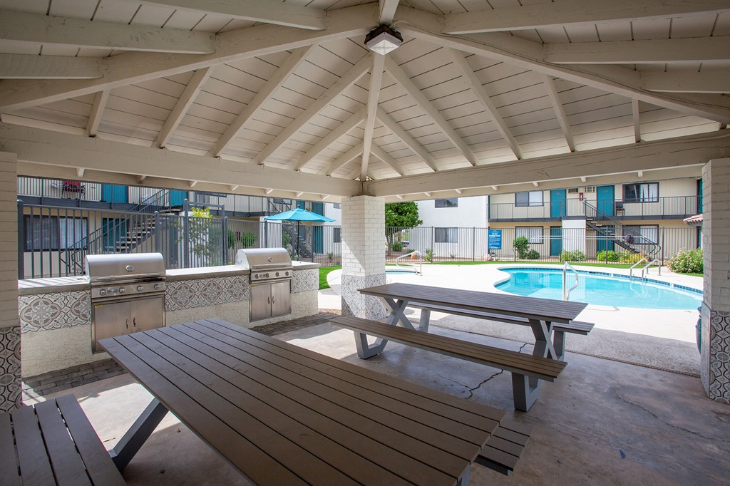 a covered patio with a picnic table and a pool