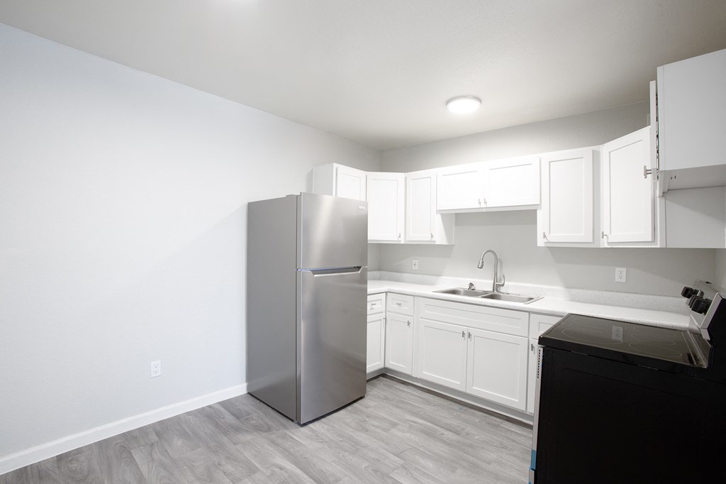 a kitchen with white cabinets and a stainless steel refrigerator