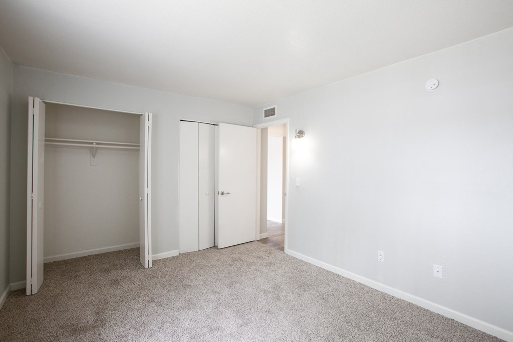 an empty bedroom with white walls and a closet