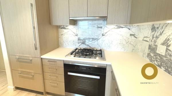 A kitchen with a marble backsplash and a stove top oven.