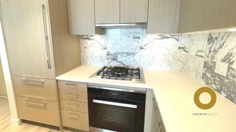 A kitchen with a marble backsplash and a stove top oven.