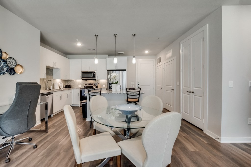 a dining room and kitchen with a glass table and chairs