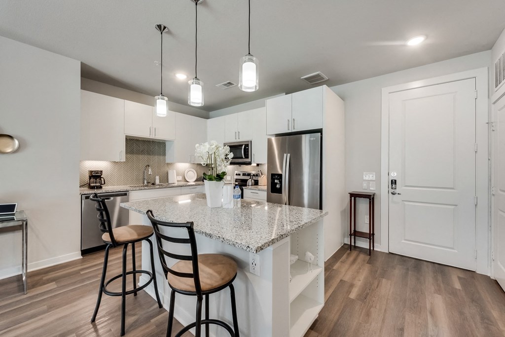 an open kitchen with a marble counter top and bar stools
