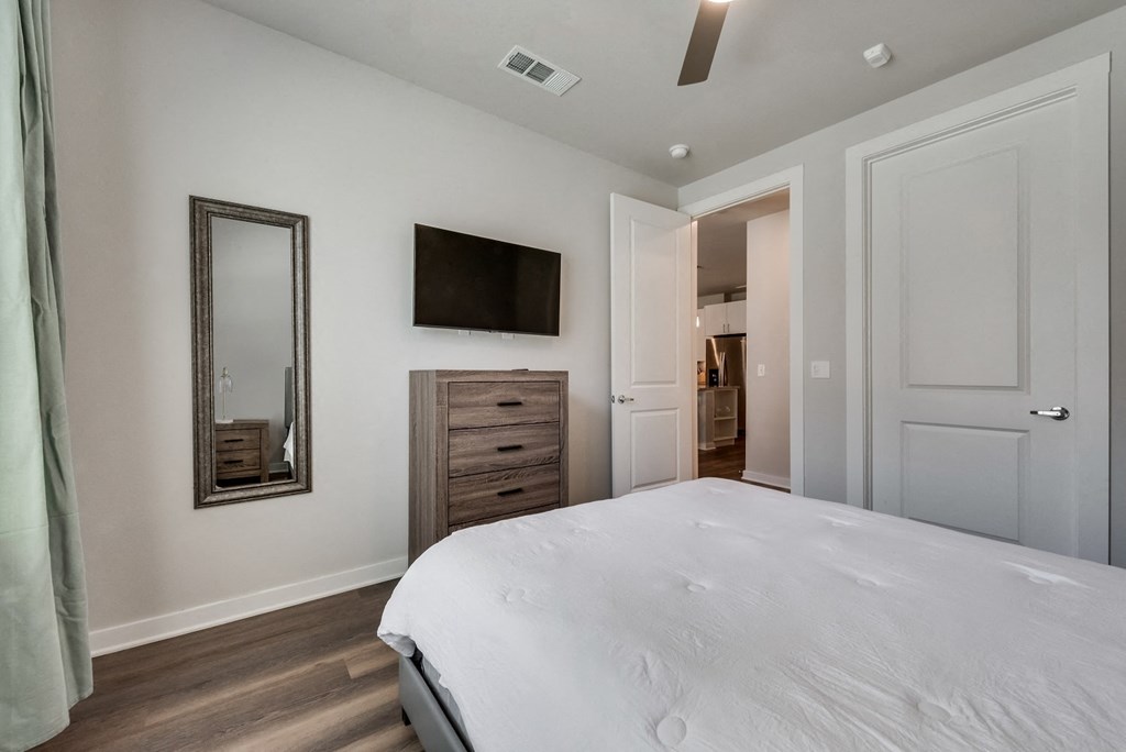 a bedroom with a white bed and a mirror on the wall