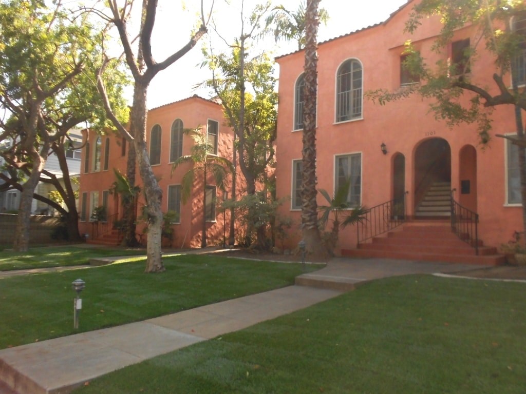 the exterior of a pink house with green grass and trees