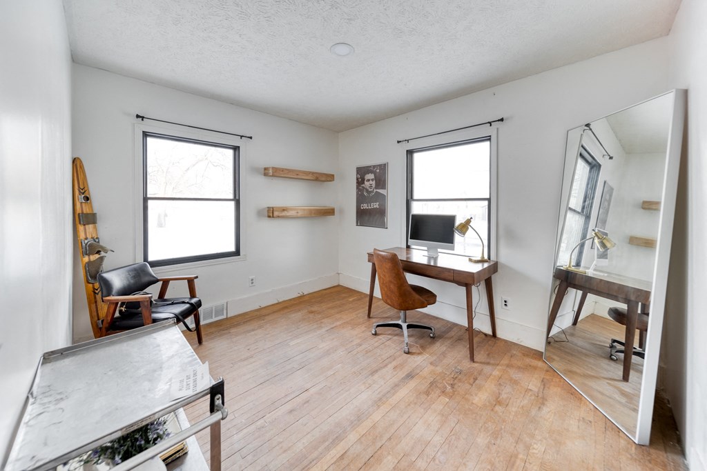 a living room with a wooden floor and a desk with a computer